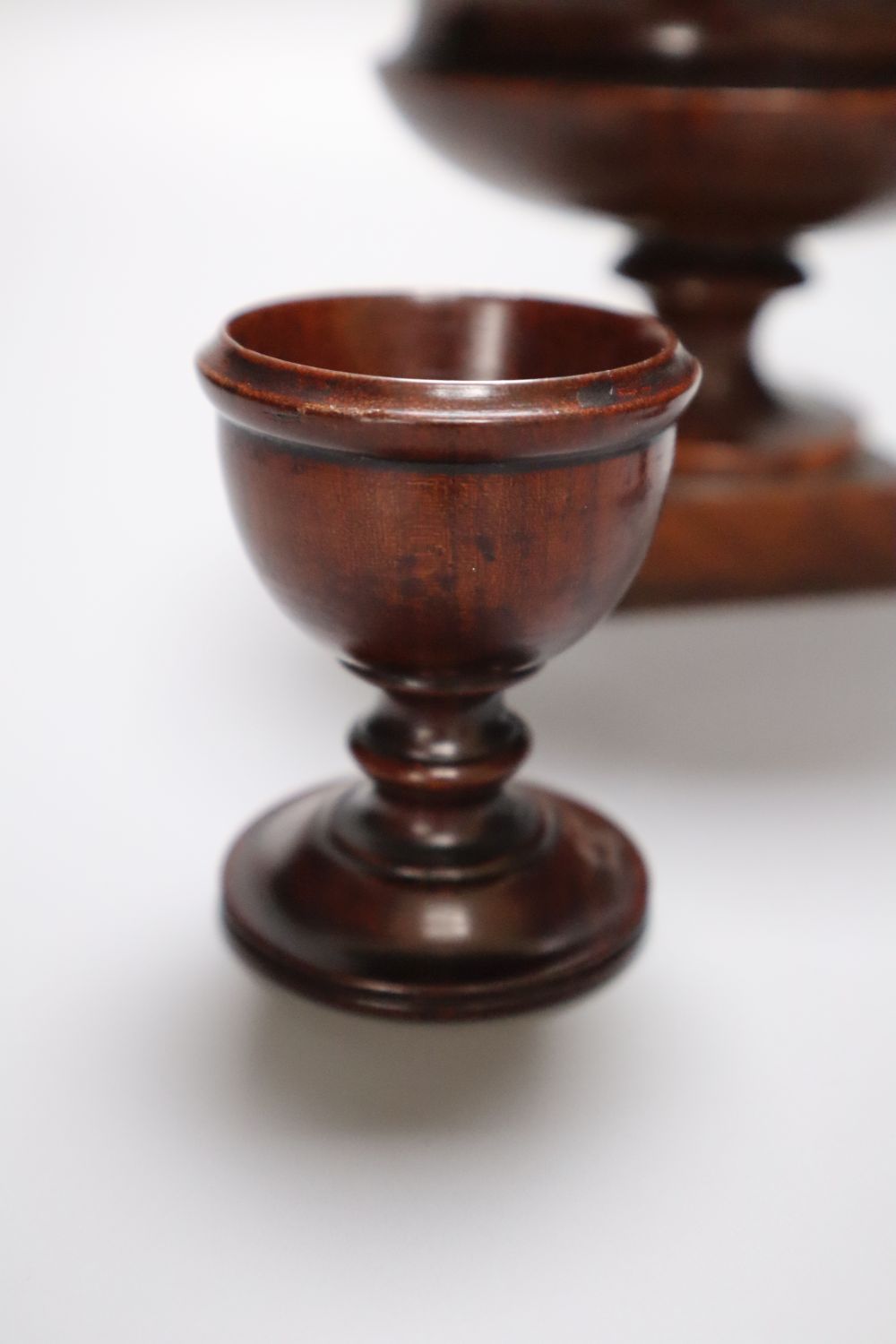 A 19th century turned amboyna urn, 11cm and two late Georgian turned mahogany egg cups, 6.5cm